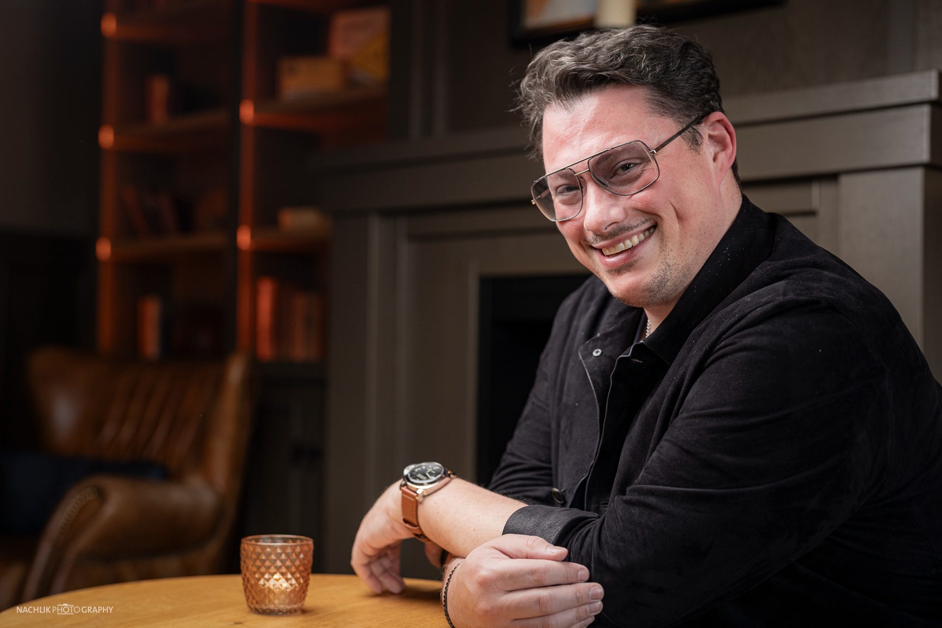 Ricardo Marinello lachend im Gespräch an einem Holztisch
