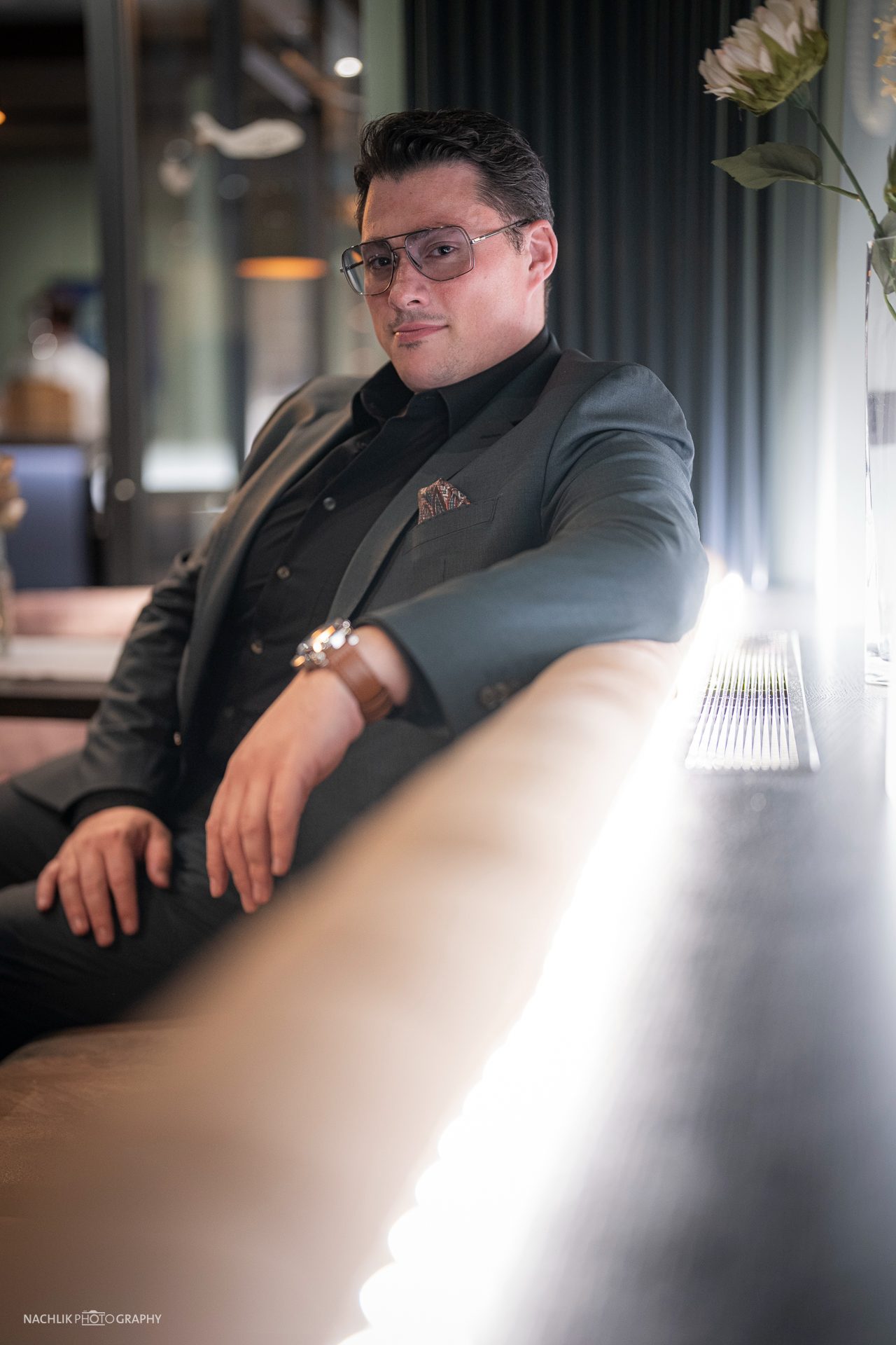 Ricardo Marinello im Anzug am Fenster sitzend, Gegenlichtaufnahme