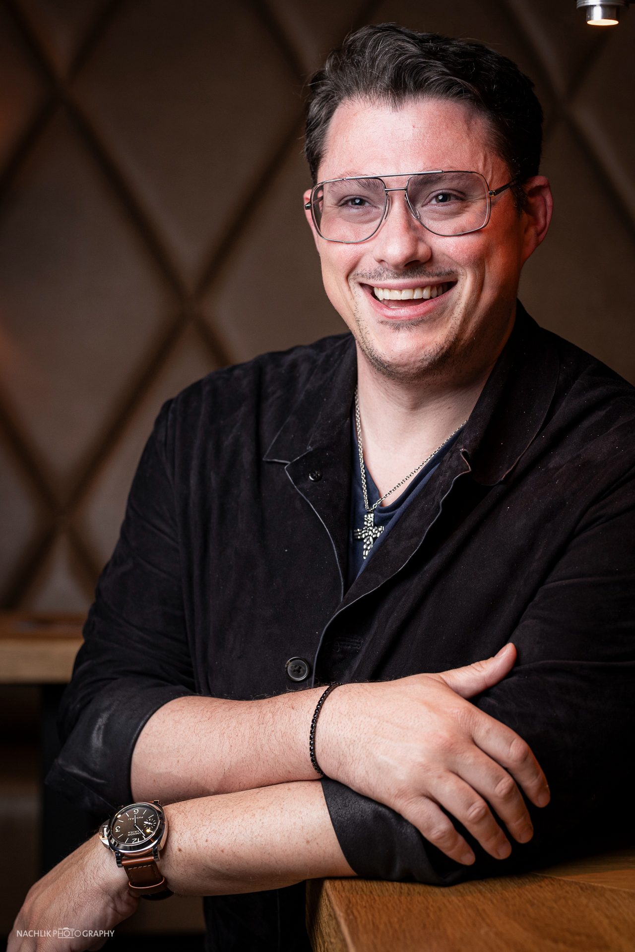 Ricardo Marinello lachend mit verschränkten Armen am Tisch