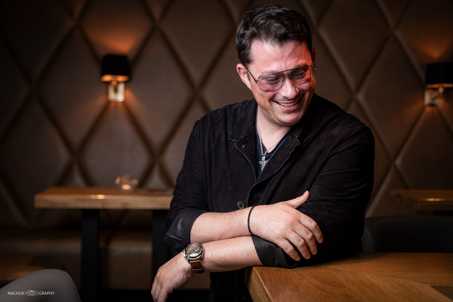 Ricardo Marinello mit verschränkten Armen auf einer Lederbank