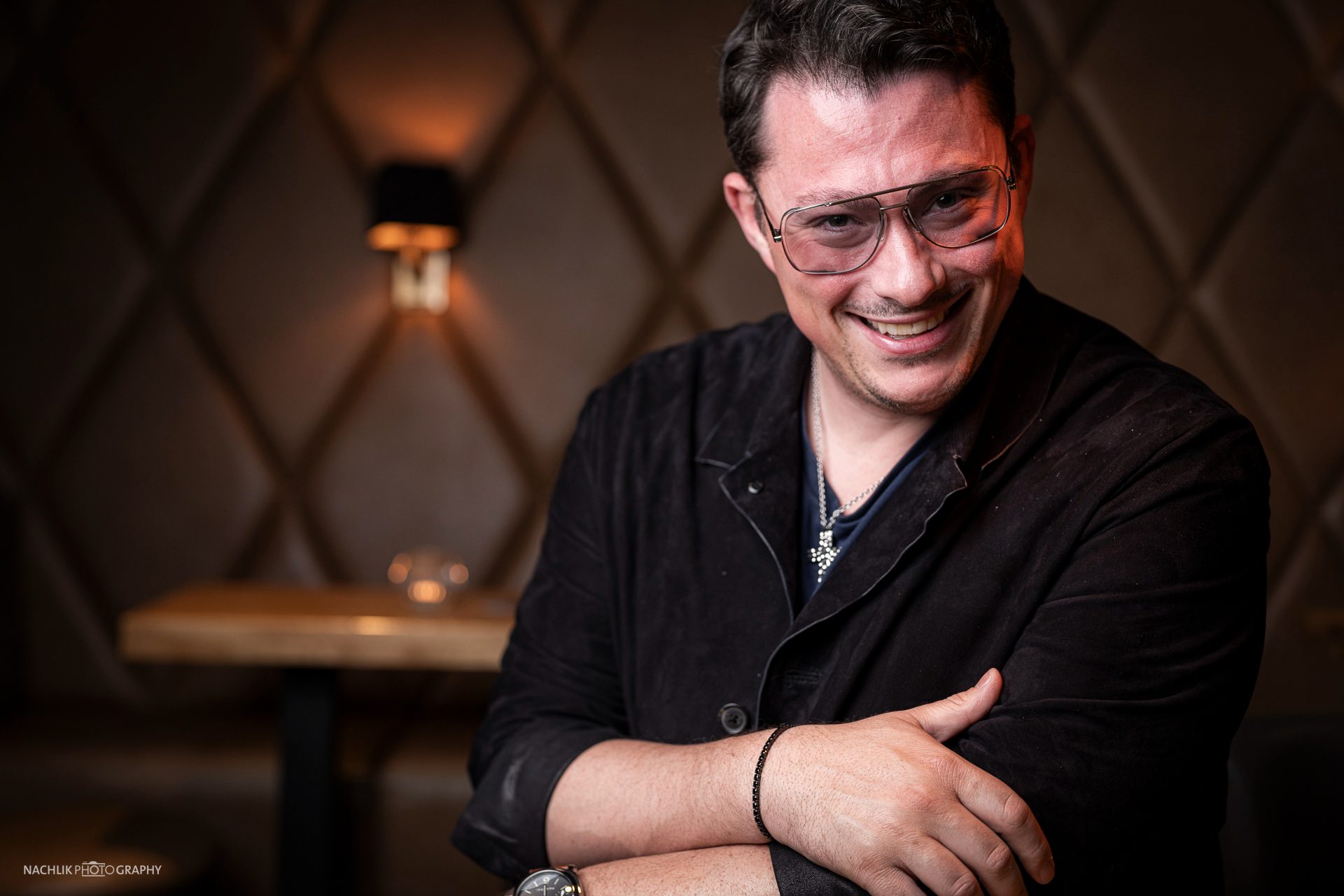 Ricardo Marinello lachend auf einer Lederbank im Restaurant